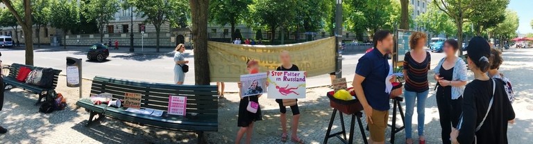 Unter den Linden bei der russischen Botschaft. Rechts eine Gruppe von Menschen, zentral zwei Menschen die Schilder halten, z.B "Stop Folter in Russland"