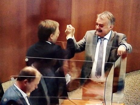 Laschet und Reul missachten Abstand und geben sich Highfive über die Plastikboxen im Landtag hinweg 