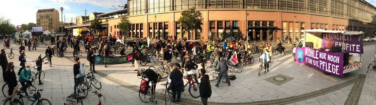 Der Dorothea Schlegel Platz mit vielen Menschen, einige haben Banner dabei. Rechts am LKW ein Banner "Kohle nur noch für die Pflege"