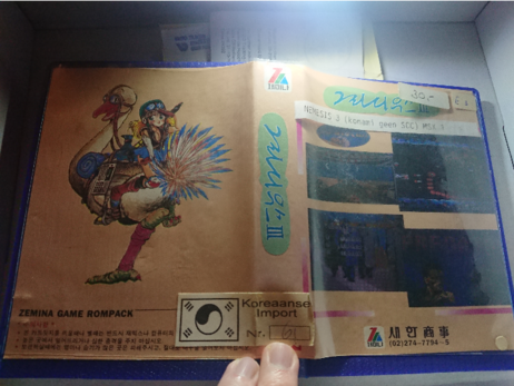 box nr 2, Zemina MSX cart.
A generic pink box with the Zemina logo, with on the front various unrelated game screenshots, and on the back a cartoon girl on the back of an ostrich.
The spine and front have Korean Glyphs, which probably spell out the Korean name for Nemesis III.

Dutch added label says Nemesis III (Konami, no SCC), MSX1. Old price label indicates "30,-”, which likely is in Dutch pre-Euro Guilders.

Also a Dutch label which says "Korean Import nr 61"