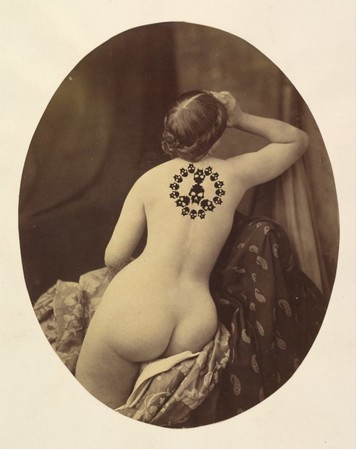 naked woman in sepia tones photographed, has a tattoo of the book of Nod skulls between her shoulder blades