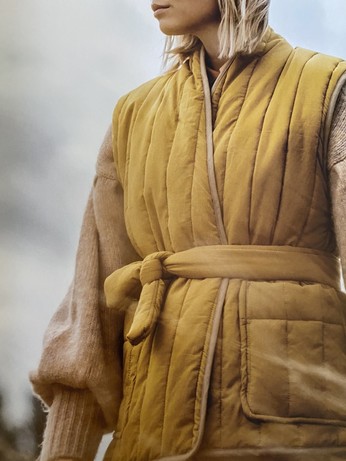 Quilted sleeveless vests on adults and children , some belted, done with metal snaps