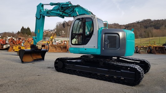 Baumaschine Bagger Bild Kobelco Kettenbagger SK 200 in grün . Bagger steht vor einem Waldstück. Images used Kobelco Excavator