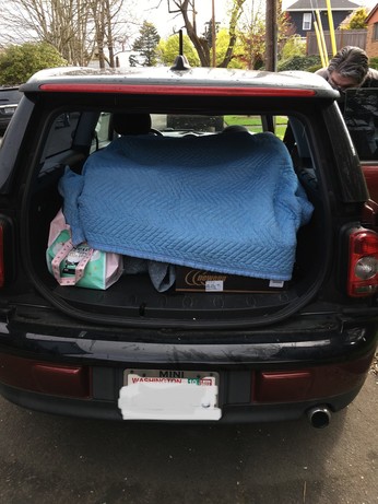 The back of a 2009 Mini Clubman containing a 1890s Singer treadle sewing machine under a packing blanket.