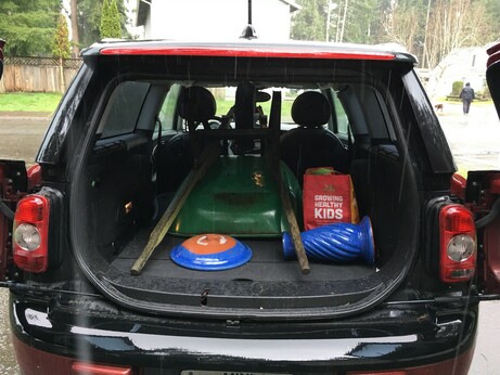 The back of a 2009 Mini Clubman containing a green wheelbarrow and a blue birdbath.
