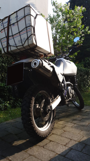 A motorcycle with a big 1084S monitor box on its luggage rack.