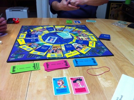 Picture of the board game Kohle, Kie$ & Knete (the game known as I'm the Boss in the United States) laid out on a table and in progress.

Image CC attribution licensed by Board Game Geek user Christopher Ross, jedijawa74: https://boardgamegeek.com/image/1511781/im-boss