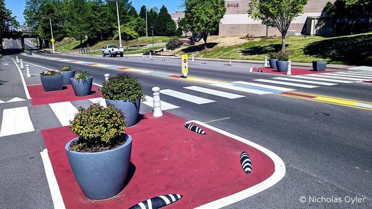 Foto einer Straße in Memphis: Zu sehen sind unterschiedliche Schutzelemente wie Blumenkübel, Armadillos und farbige Markierungen, die zu einer besseren und geschützteren Infrastruktur für Fahrradfahrende und Fußgänger führen.
