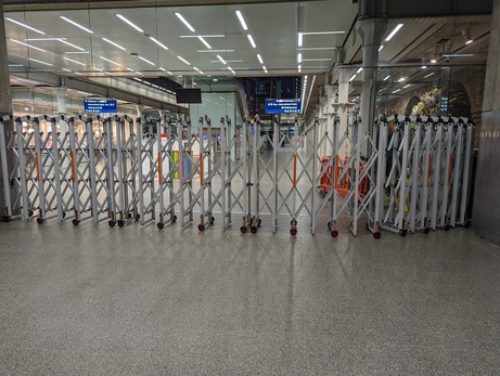 A barrier across the platform with lifts and shops behind