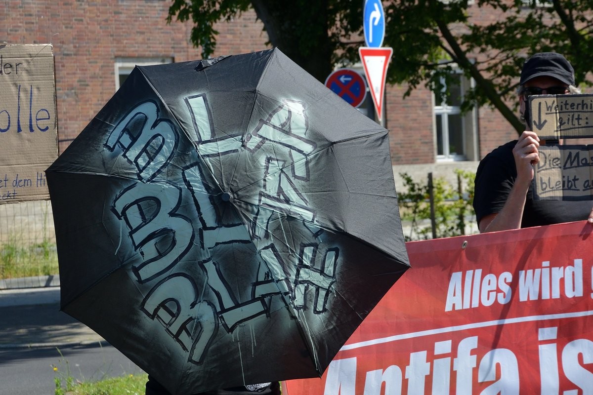 Ein schwarzer Regenschirm mit der Aufschrift BLA BLA BLA wird vom Gegenprotest Richtung Querdenker gehalten.