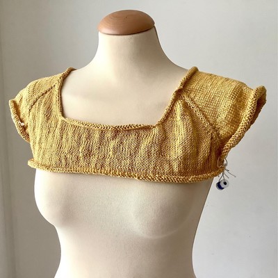 Knitted yellow tee, partially done, shown from the front on a mannequin 