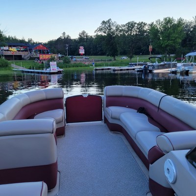 a pontoon pulling up to the dock of a lakeside restaurant