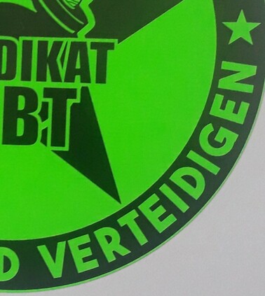 Ein Viertel eines neon grünen Kreises mit der Aufschrift: "Diktat- bt" und "verteidigen "