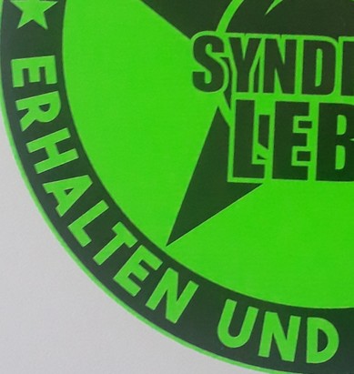 Viertel eines neon grünen Kreises mit der Aufschrift: " Erhalten und" und "Syndi - Leb"
