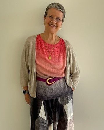 A woman wearing a knit shirt in red to dark gray gradient colors. Over it, she wears a cardigan.
