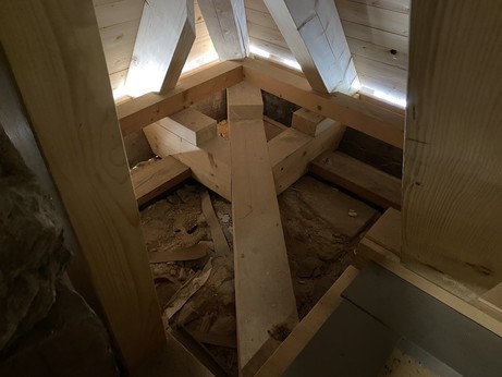 Detailansicht einer neu renovierten Dachbalken-Konstruktion auf altem Mauerwerk. Detail der Dachauflage am Eck des Gebäudes mit einem dicken Balken, der in einem Dreizack-förmigen Ende.