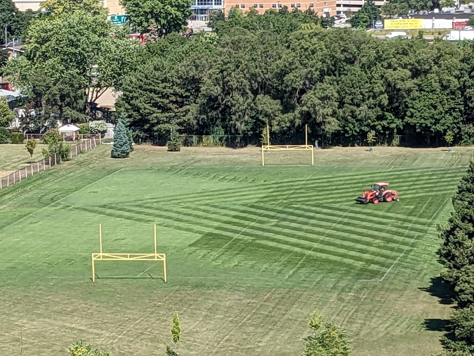 Tractor cutting grass on a soccer field in a triangular pattern
