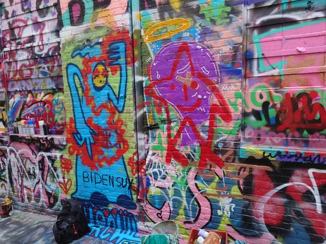 a star with a halo, a blue robed figure manipulating red energy with their hands, and the words "biden sux"