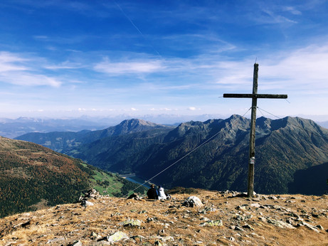 The cross at the summit of Mt. Mutegg and mountain peaks in the distance