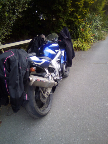 Our old racy royal blue R6 Yamaha-YZF which grandma's inheritance wonderfully got us this nearly new many years ago, in the park with riding gear draped over it.