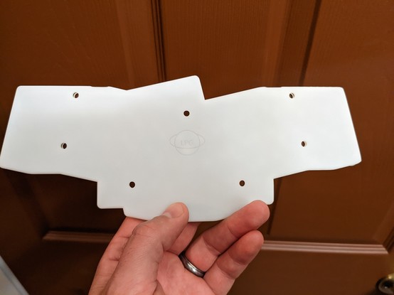 Bottom side of a white resin unibody split revxlp keyboard, with screw holes and centered logo.