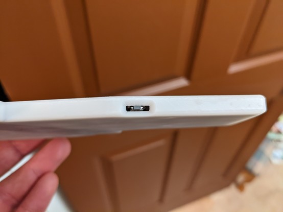 Edge view of the resin case, showing the reset button through a slot.