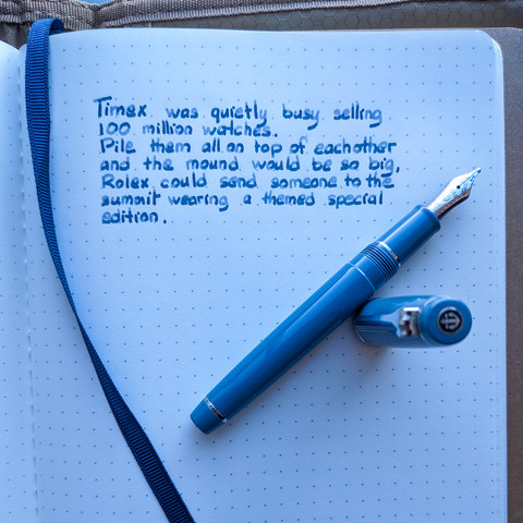 Fountain pen next to the quote "Timex was quietly busy selling 100 million watches. Pile them all on top of eachother and the mound would be so big, Rolex could send someone to the summit wearing a theme special edition."
