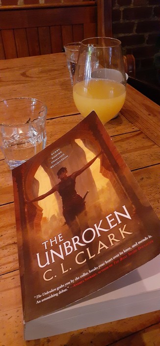 Cover of The Unbroken, a military fantasy novel by C. L. Clark. There's also a mimosa in the background. 