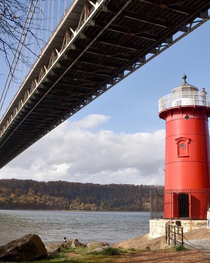 Red lighthouse under large bridge