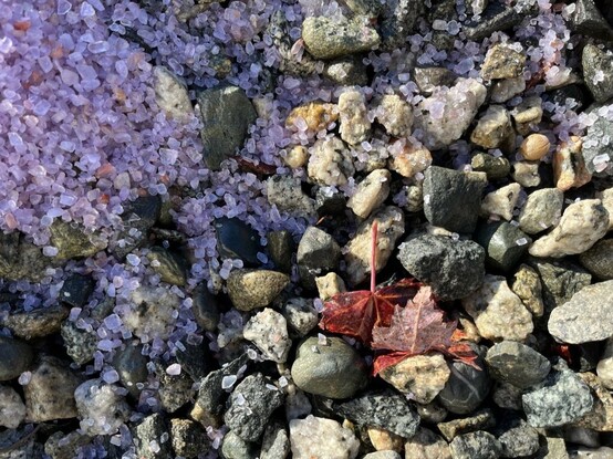 Lavender road salt granules spilling onto granite and basalt pebbles