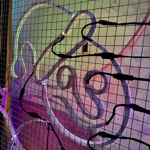 The reverse side of an LED neon-style artwork featuring a face wearing a bobble hat in white, red and green tones