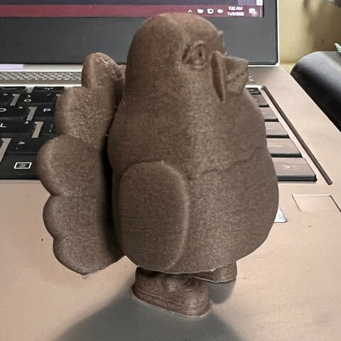 Side view of 3-D printed cartoonish turkey standing on a laptop