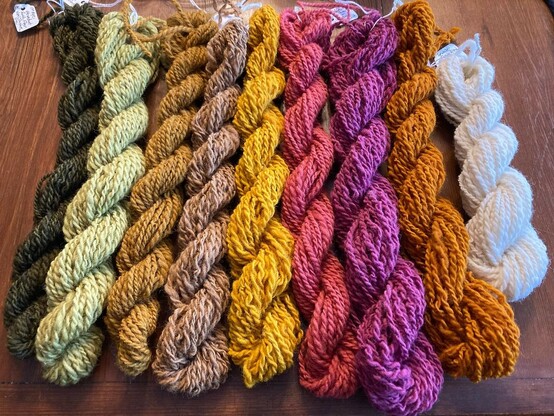 Naturally dyed wool yarn in mini skeins and in vivid colors ranging from deep ochre to purple, pink, browns and green.