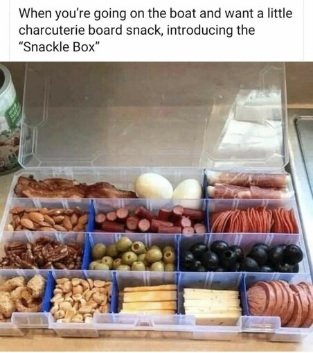 A small tackle box filled with charcuterie. The caption reads: 'When you're going on the boat and want a little charcuterie board snack, introducing the "Snackle Box"'