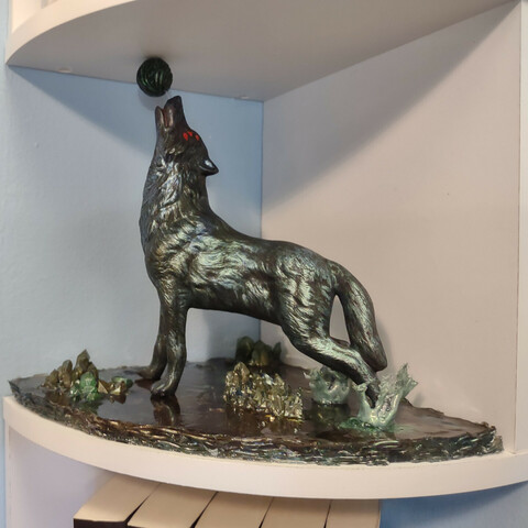 A profile view of a six-eyed black wolf statuette on a resin base, playing with a black & green ball (orb of fen'harel) 