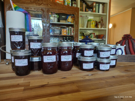 A butcher block island covered in a variety of home canned jellies, jams, & compotes.