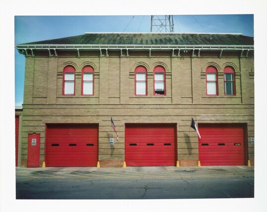 A old firehouse in Lockhart, Texas with large red doors.