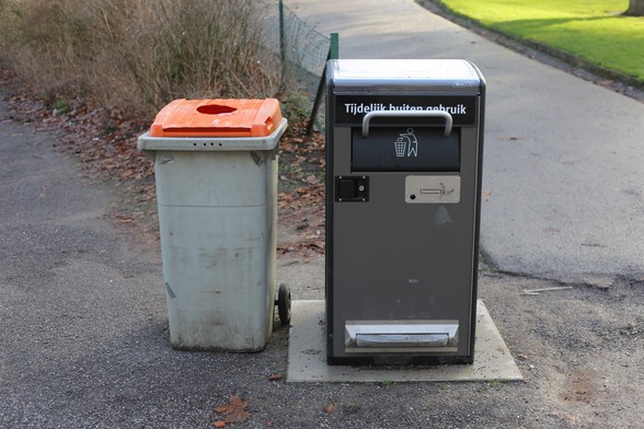 An out of order smart trash can, with a plastic trash container standing besides.