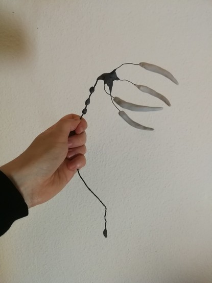Hand holding a rudimentary Hoa'uld skeleton made from wire and polymer clay, including four massive fangs.
