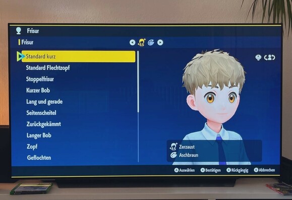 Foto von Pokémon Purpur auf meinem TV. Zu sehen ist der Charakter-Editor mit der Auswahl “zerzaust” für die Frisur.