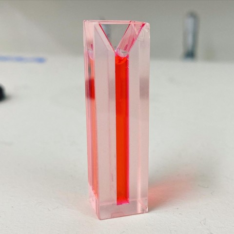 A cuvette filled with bright red liquid against a white background.