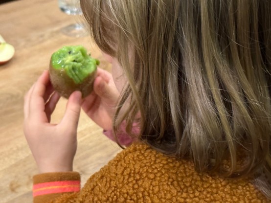 Photo of my daughter eating a kiwi with its peel. 