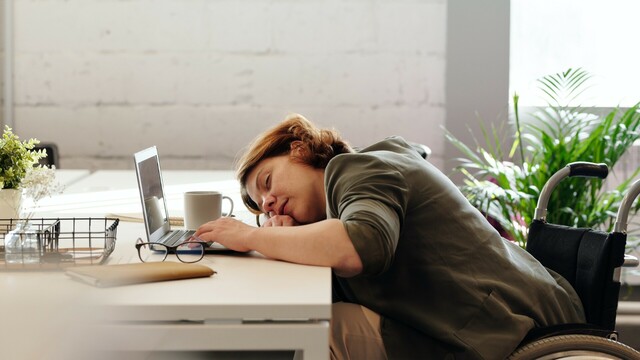 A woman has fallen asleep in front of her laptop.