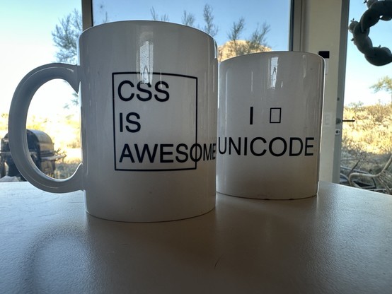 Two white coffee mugs: “CSS is awesome” with the words awesome sticking out beyond the frame “I [empty square] UNICODE”