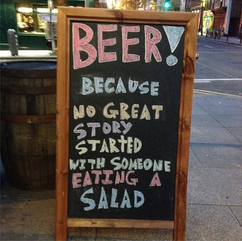 This is a photograph of a sign outside a pub in Dublin, Ireland. It reads: "Beer! Because no great story ever started with someone eating a salad."