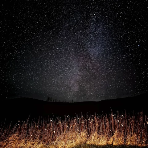 A starry sky.  The milky way meets dark hills.