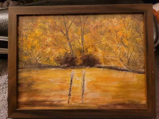 Watercolor painting of fall trees and water.
