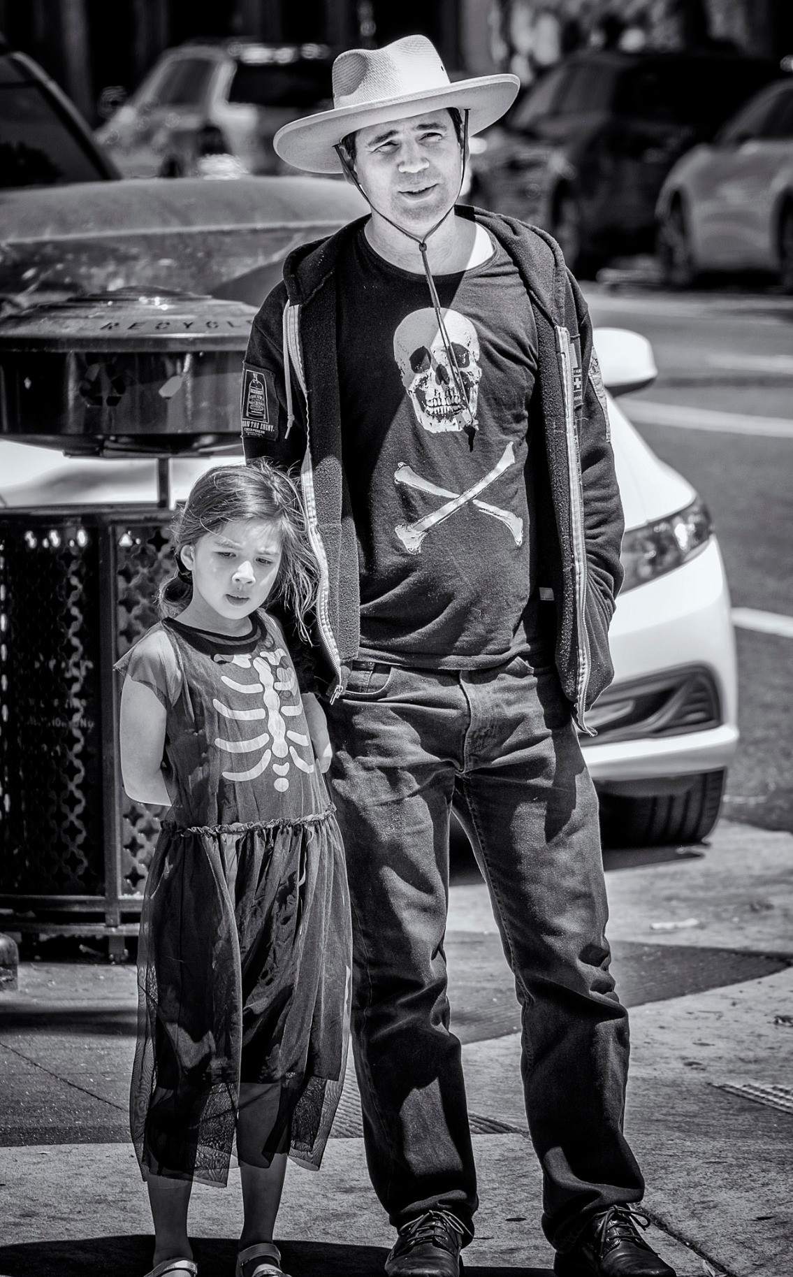Father and daughter dressed in skeleton shirts on a street corner in San Francisco.