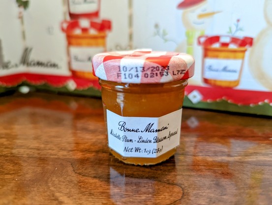 Front of tiny jar of Mirabelle Plum Linden Blossom Spread. No discernable features to the jam other than a nice orangey brown color