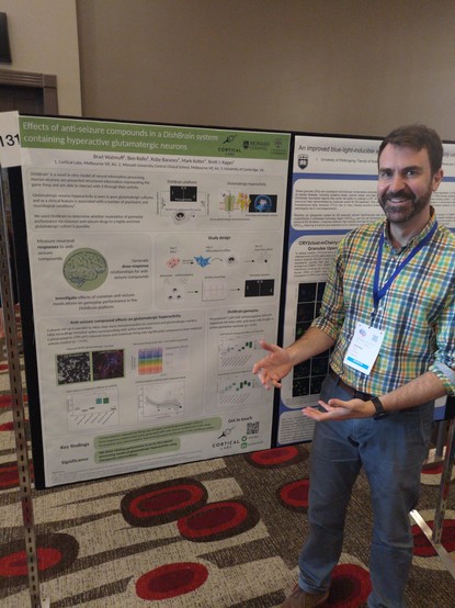 Portrait of man standing next to a scientific poster and pointing at its results
